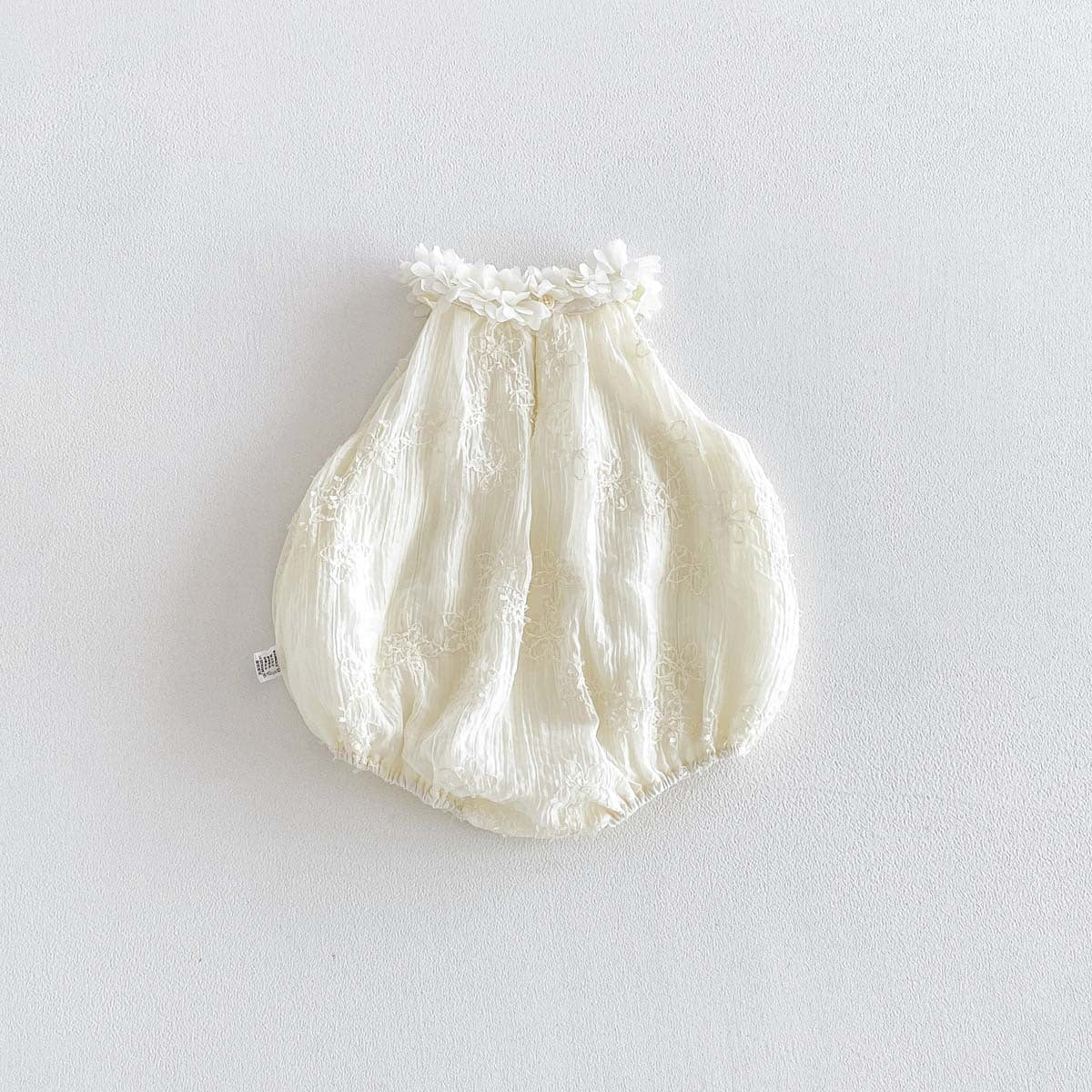 Ivory floral garland romper flat lay on neutral background