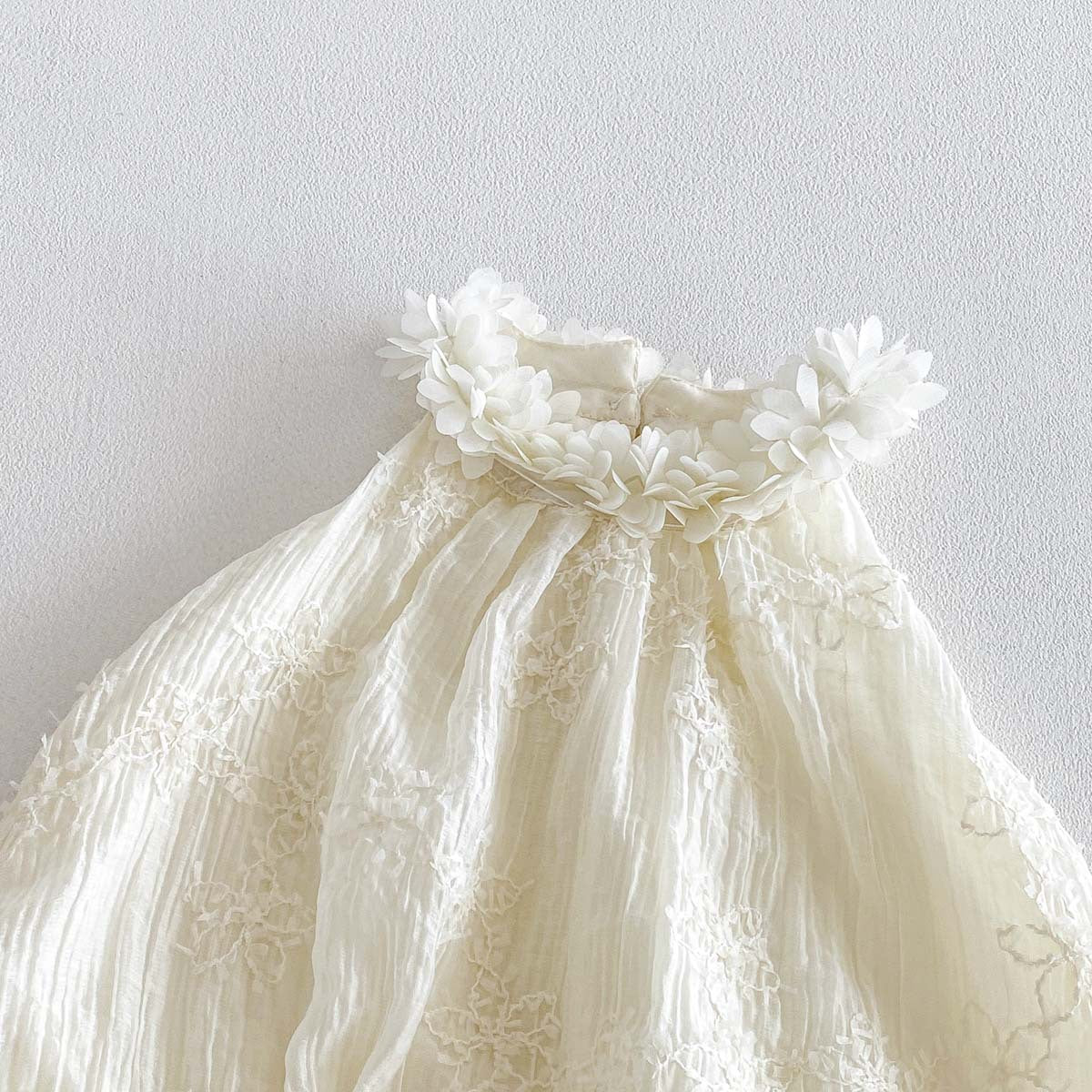 Close-up of 3D flower collar on ivory baby bubble romper
