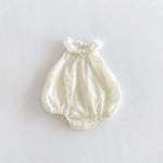 Ivory sleeveless bubble romper fabric and flower detail close-up