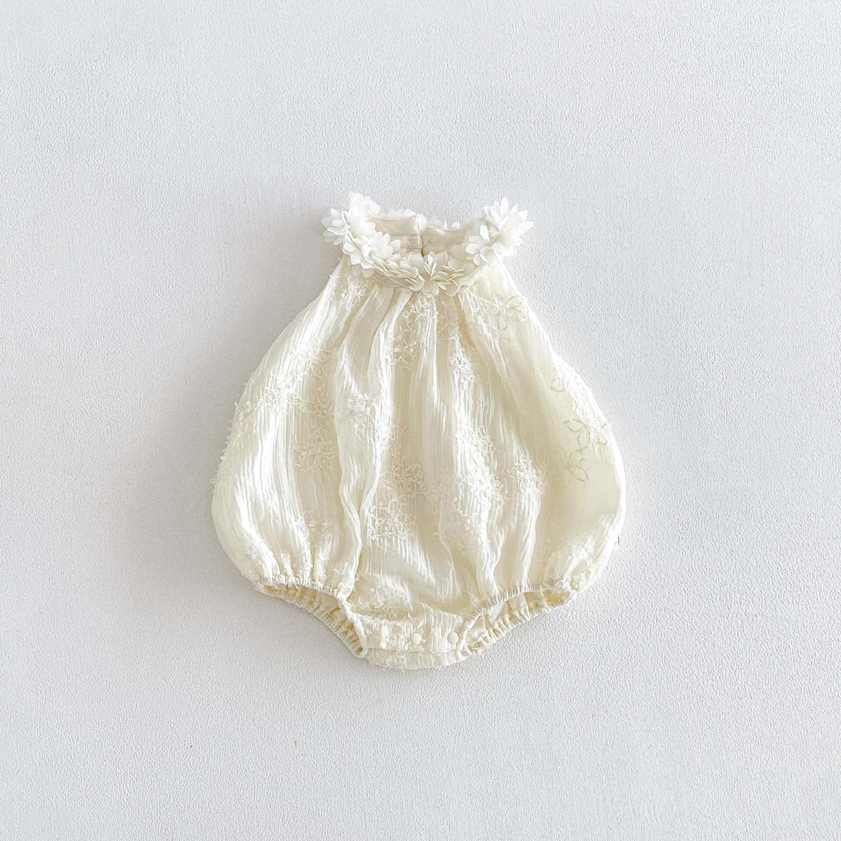Ivory sleeveless bubble romper fabric and flower detail close-up