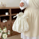 Ivory sleeveless bubble romper with flower collar detail, side view